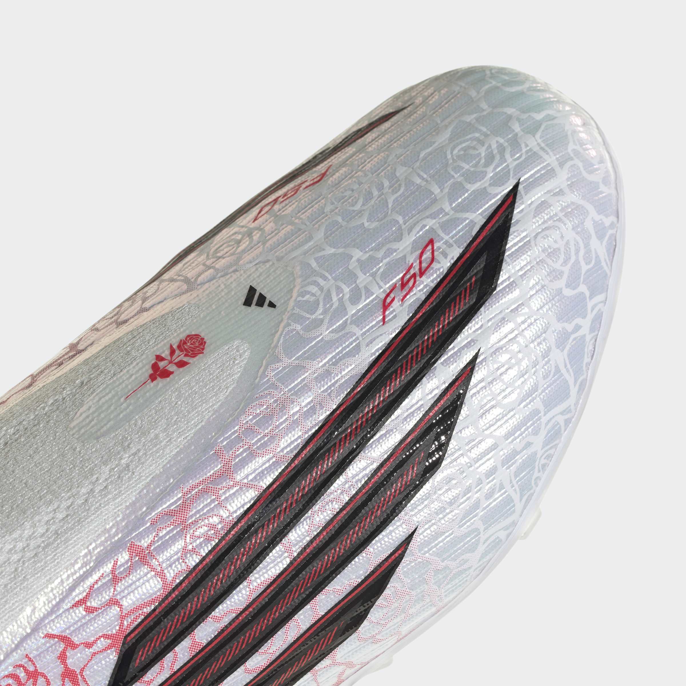 תקריב של נעל כדורגל אפורה עם דוגמת ורדים, קווים שחורים ואותיות F50 באדום