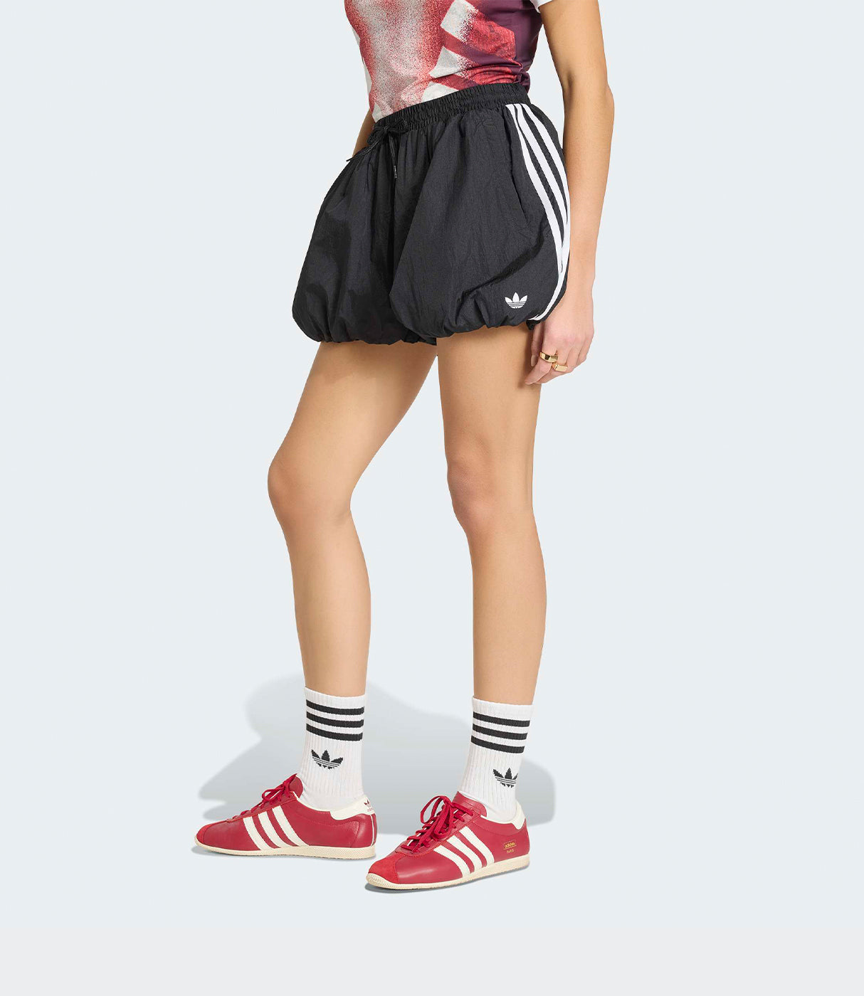 דגם לובשת מכנסיים קצרים שחורים עם פסי צד לבנים, גרביים ונעליים אדומות