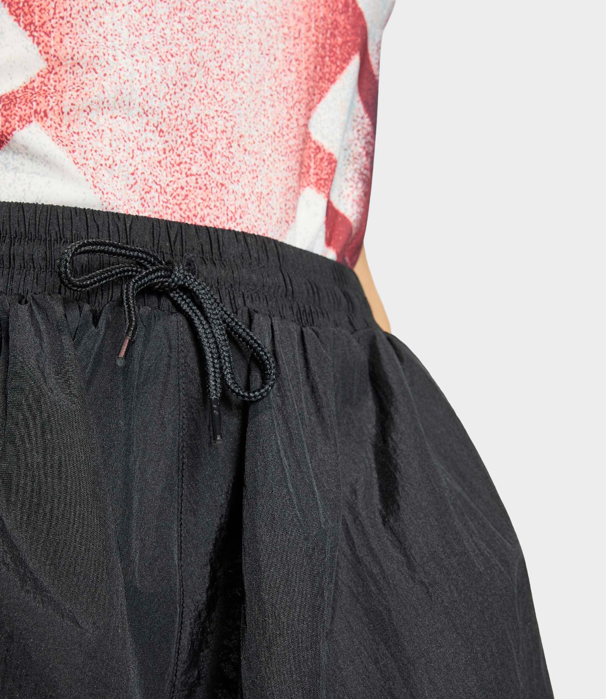 מכנסיים קצרים שחורים עם גומי ושרוך קשירה, תקריב על דגם לובש חולצה צבעונית