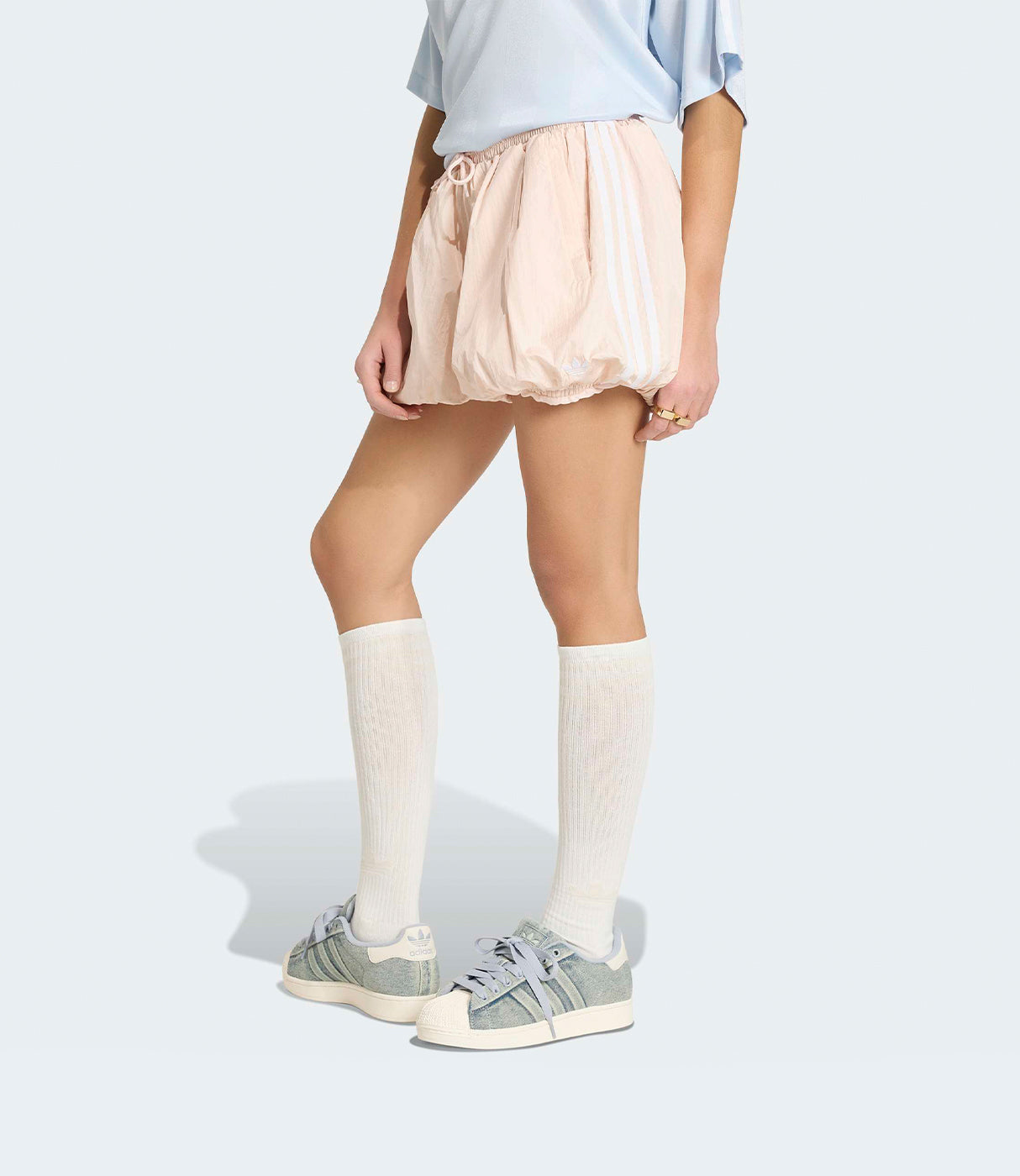 מכנסיים קצרים בגוון ורוד בהיר עם פסי צד לבנים, גרביים גבוהות ונעלי סניקרס