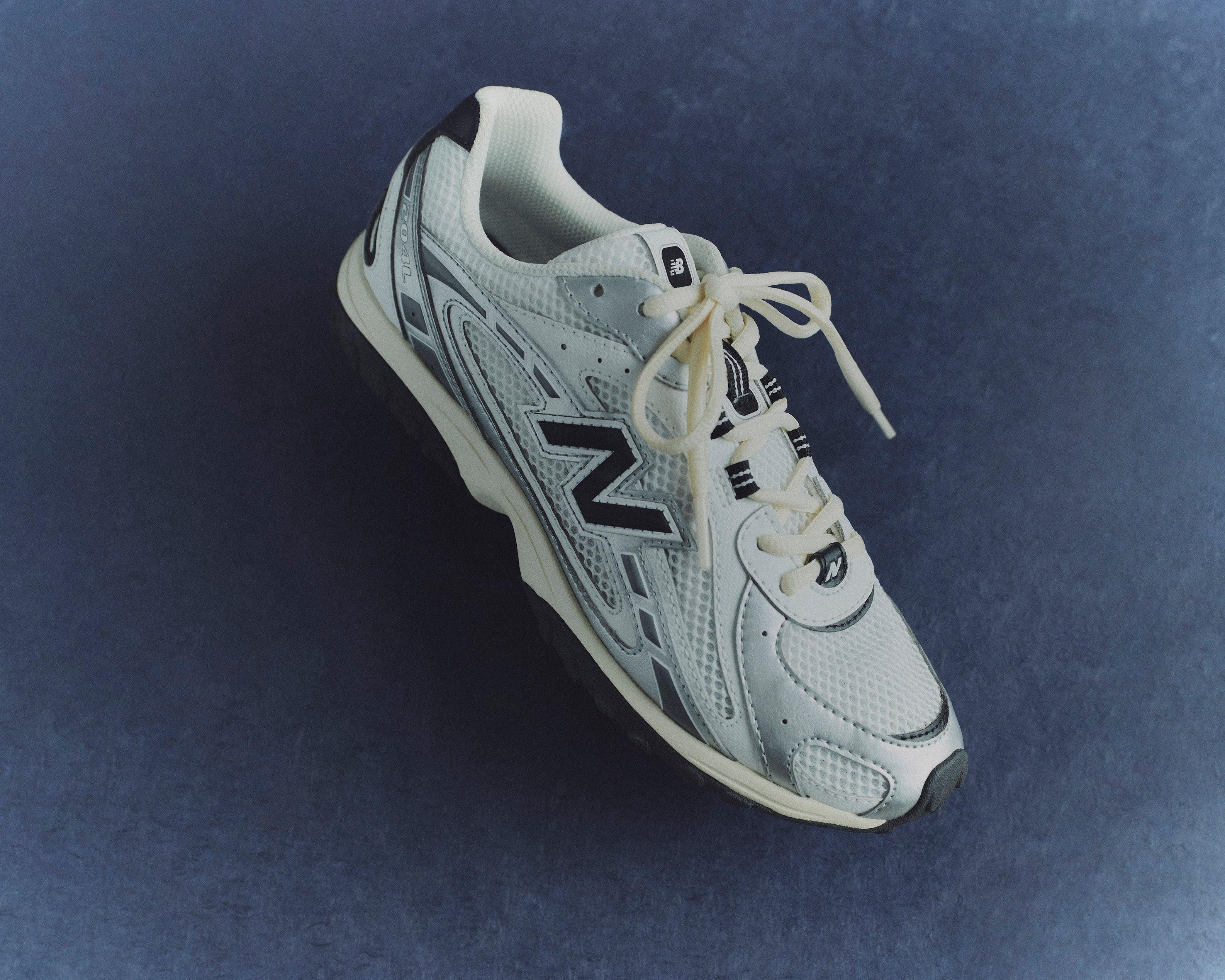 נעל ספורט ניו באלאנס לבנה עם פרטים אפורים ושחורים על רקע כחול, CHOZEN מותגים מובילים
