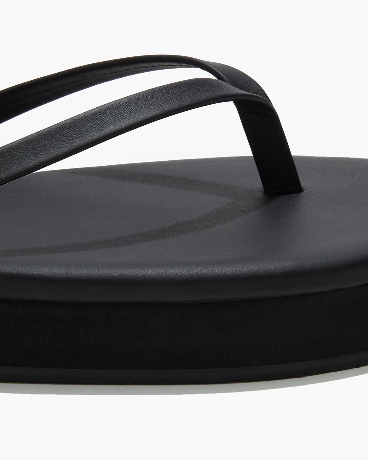 תקריב כפכף שחור עם רצועות דקות וסוליה עבה, עיצוב מינימליסטי