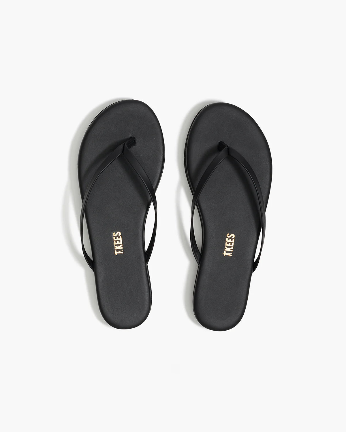 כפכפי אצבע שטוחות בצבע שחור לנשים עם רצועות דקות על רקע לבן