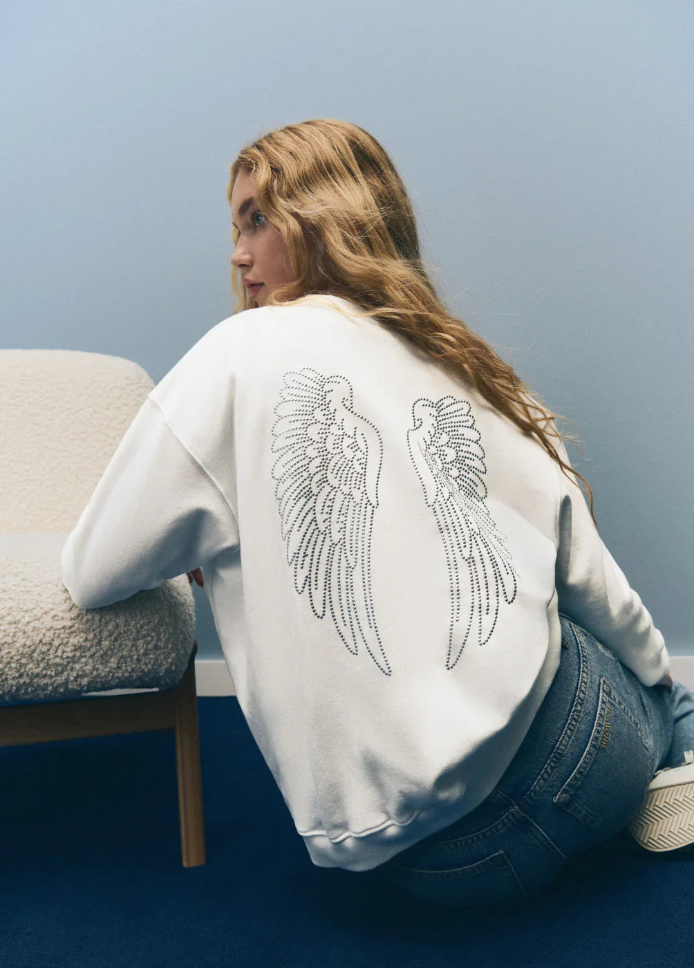 אישה עם סווטשירט לבן מעוטר כנפי מלאך, אופנה טרנדית CHOZEN, צילום סטודיו מודרני