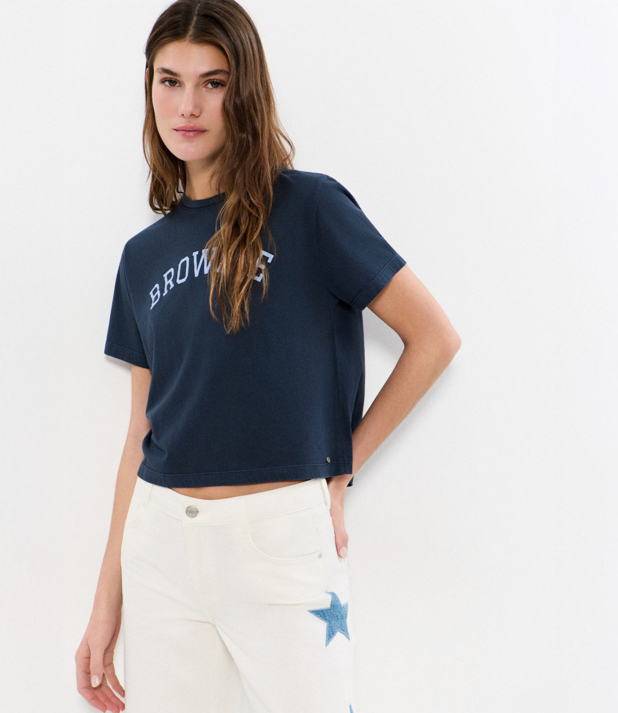 דוגמנית לובשת חולצת טי כחולה עם כיתוב BROWNS ומכנסיים לבנים עם כוכב כחול, אופנת קיץ לנשים