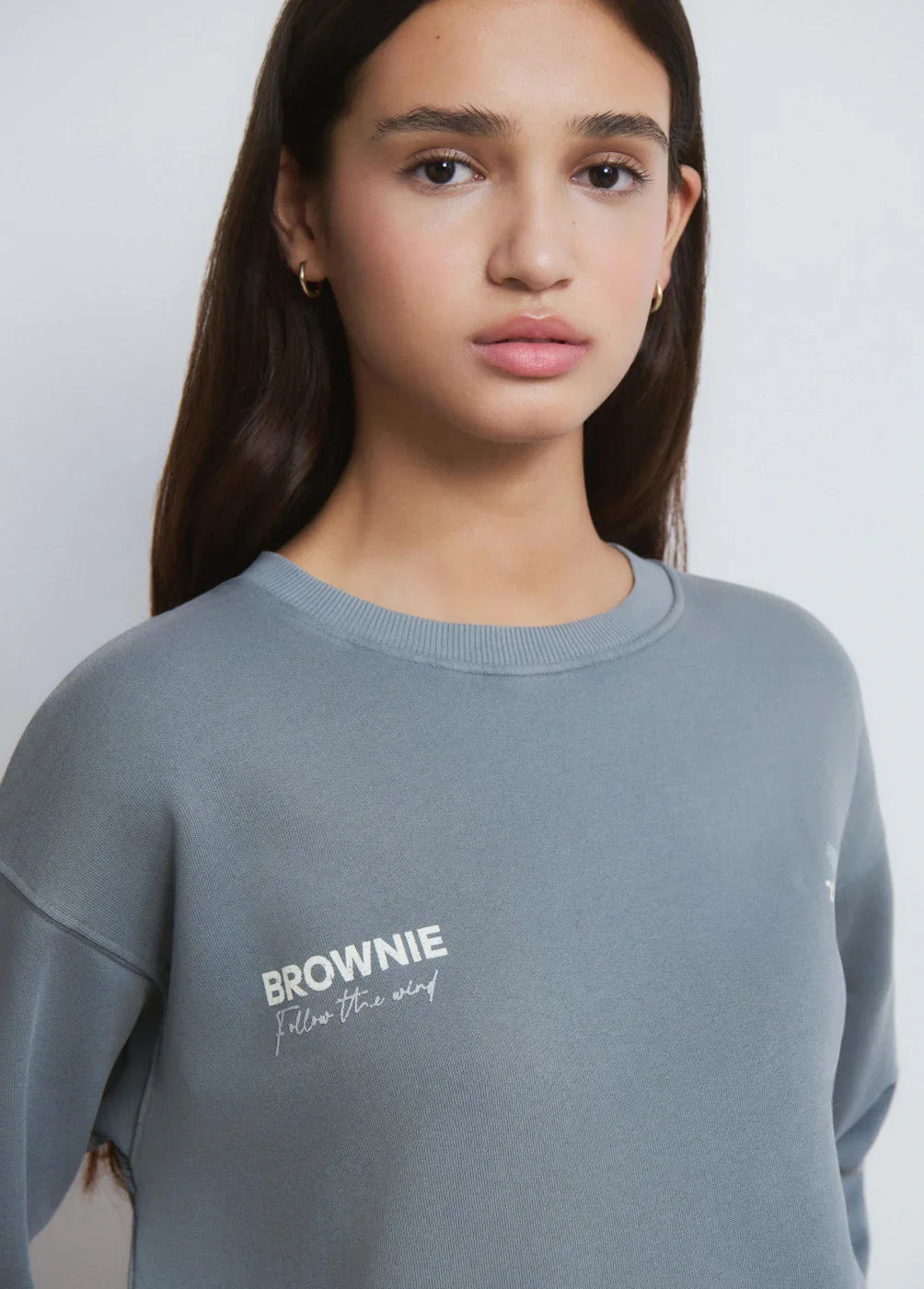 דוגמנית צעירה לובשת סווטשירט אפור עם כיתוב BROWNIE, אופנה לנשים ב-CHOZEN קבוצת אלפא