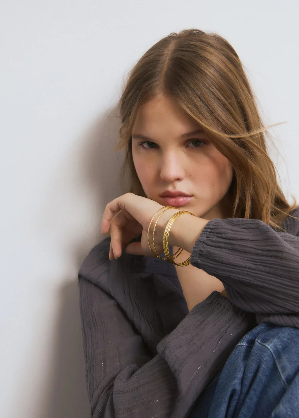 דוגמנית עם חולצה אפורה ותכשיטי זהב, צילום סטיילינג לבית CHOZEN קבוצת אלפא