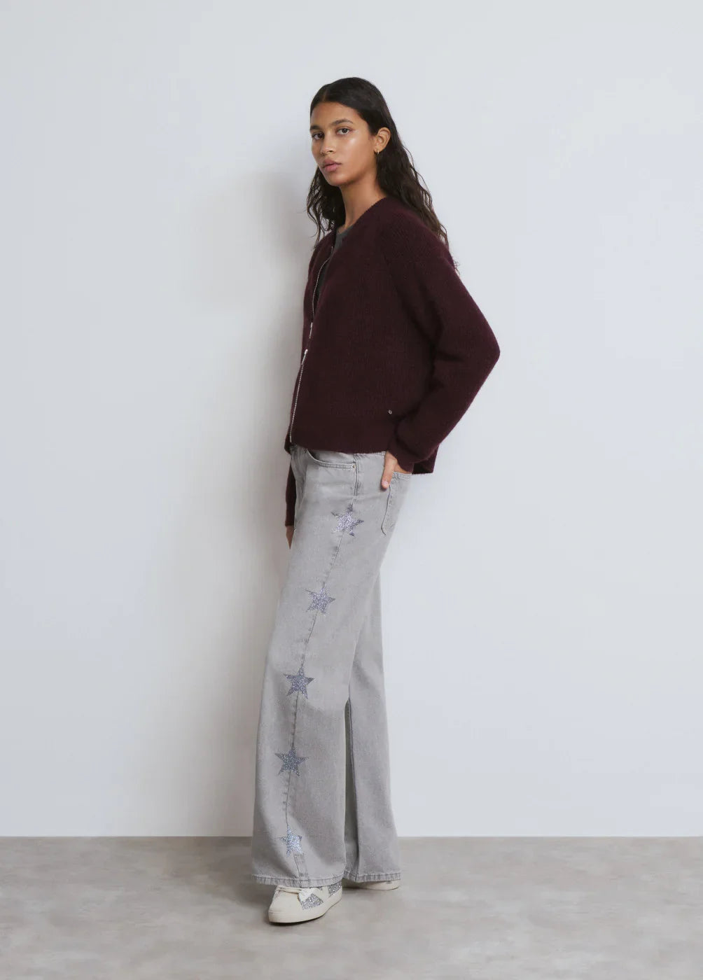 דוגמנית עם סוודר בורדו, ג'ינס אפור עם כוכבים ונעלי סניקרס, צילום בסטודיו, CHOZEN