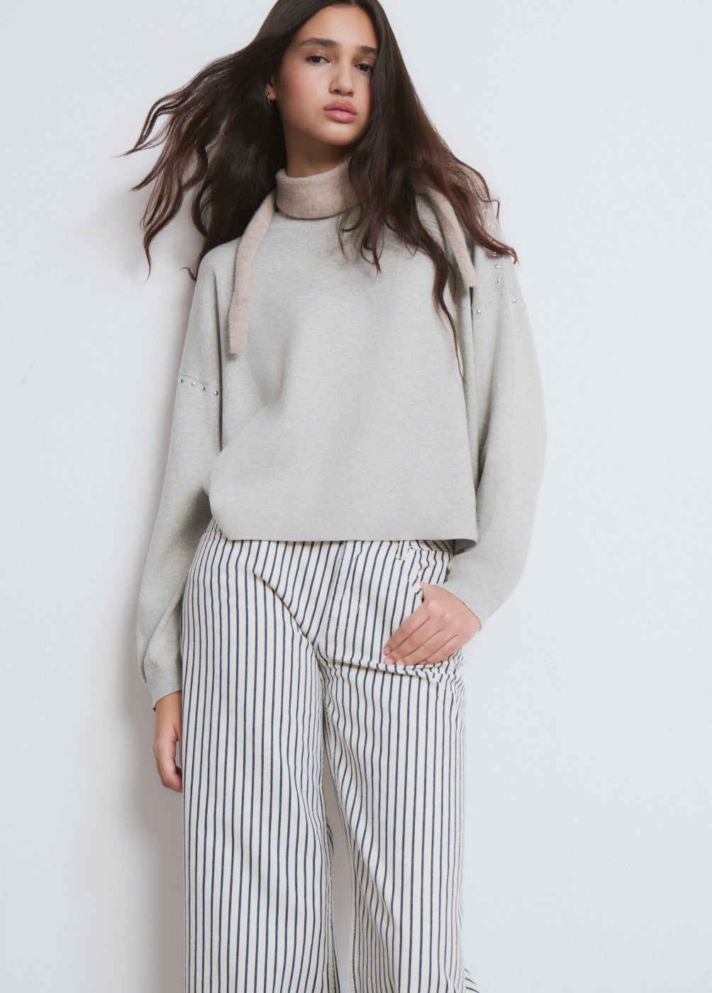 דוגמנית עם סווטשרט אפור ומכנסי פסים לבנים עם פסים כחולים, אופנה נשית חורף אלגנטית