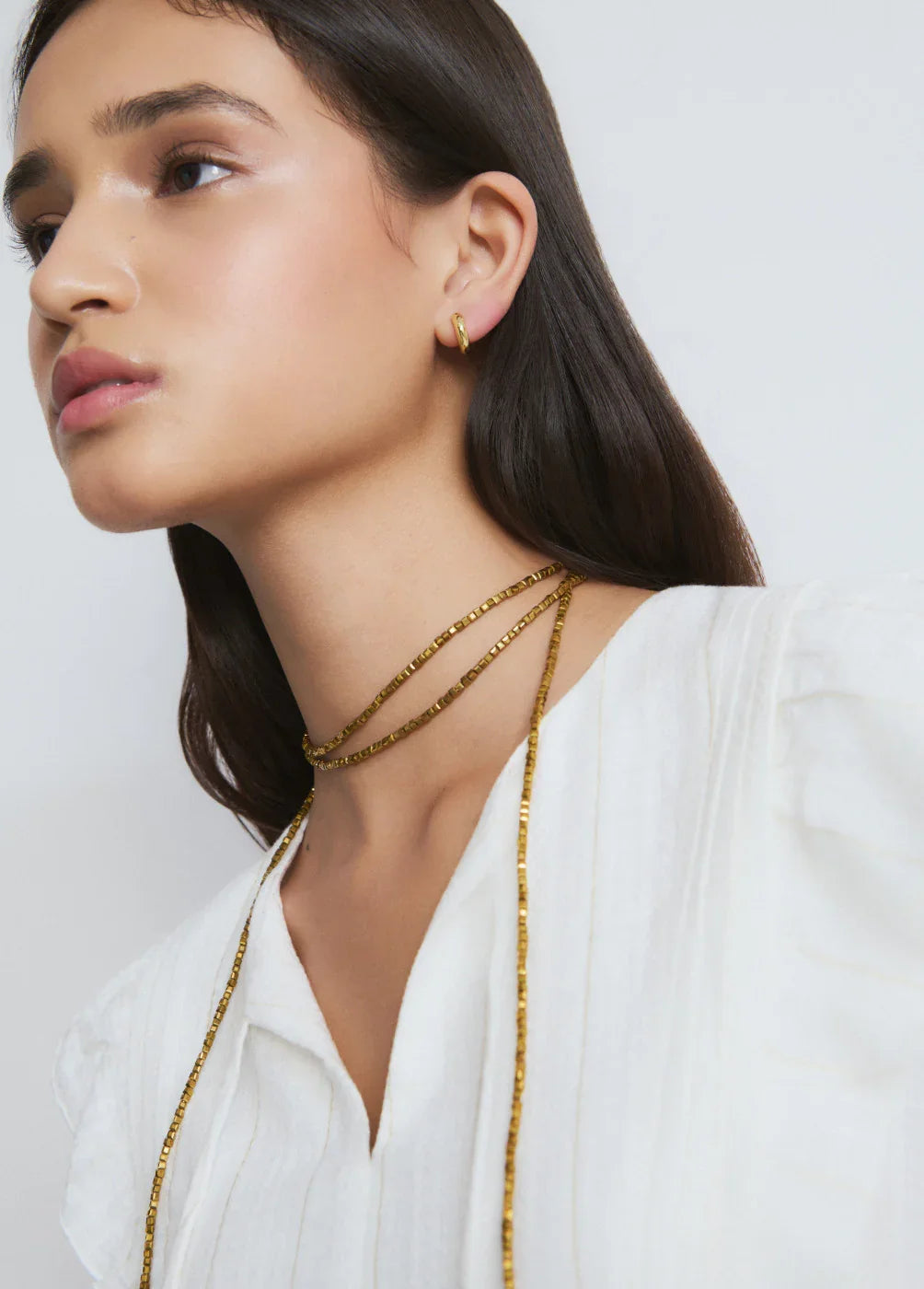 דוגמנית עונדת שרשרת זהב ועגיל זהב, חולצה לבנה, צילום תכשיטים יוקרתיים CHOZEN