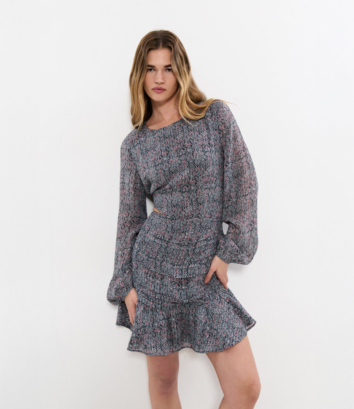 דוגמנית עם שמלת מיני בהדפס גאומטרי צבעוני, שרוולים ארוכים, רקע לבן