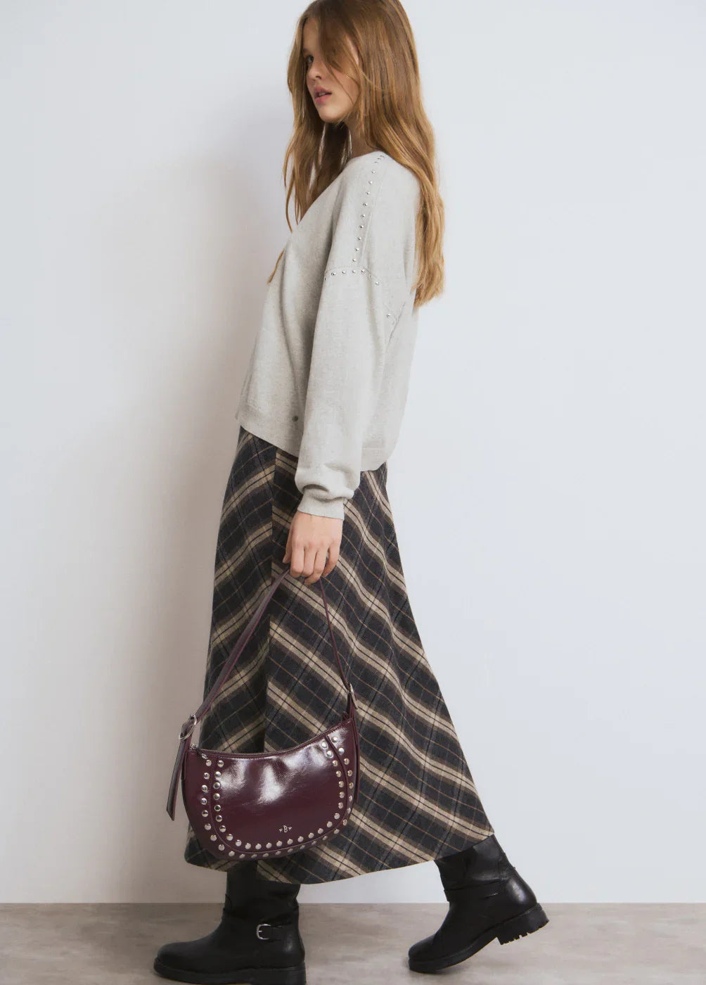 אופנה לנשים CHOZEN: דוגמנית עם סוודר אפור, חצאית משובצת ותיק צד בורדו בעיצוב יוקרתי