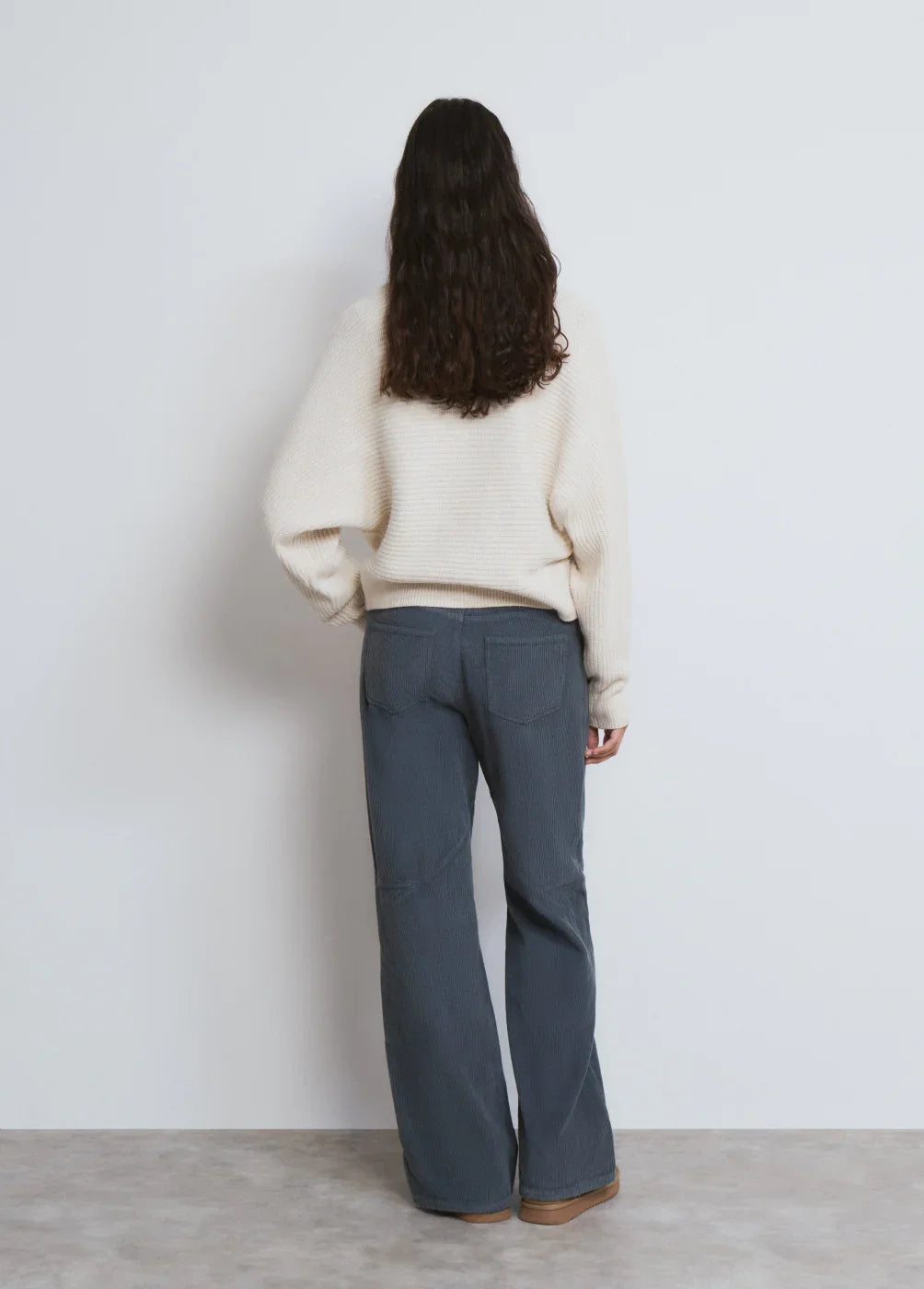 דוגמנית לובשת סוודר לבן ומכנסיים כחולים רחבים, צילום סטודיו CHOZEN